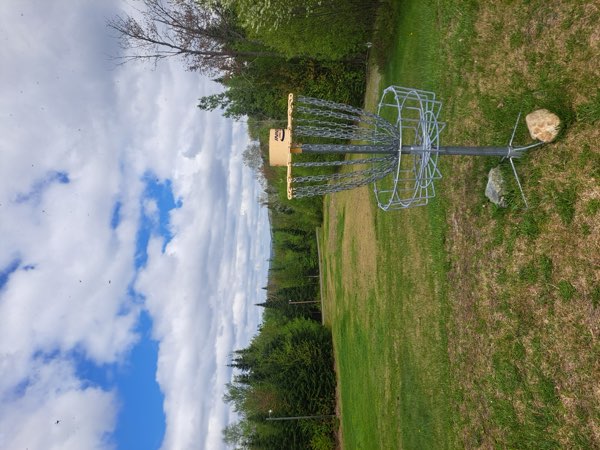 A basket in an open field under heavy cloud, with hills in the distance