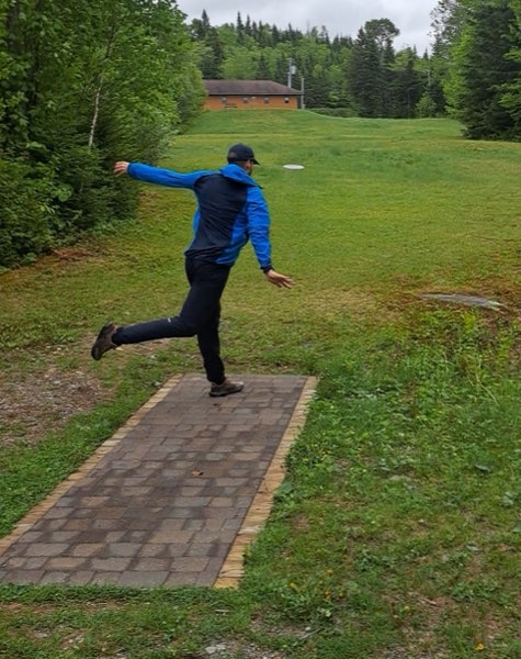A player drives off the paved tee pad, disc in flight